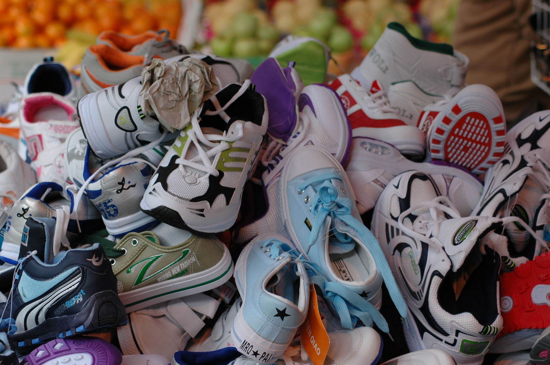 Pile of shoes with fruit in the background.