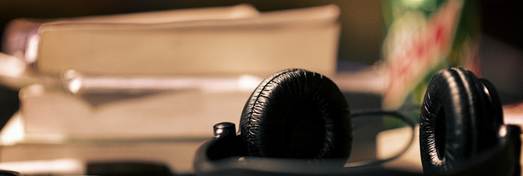 A pair of padded headphones resting atop some books, seen edgewise. 