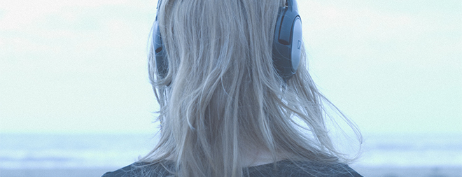 Woman wearing headphones, cropped from rear. 