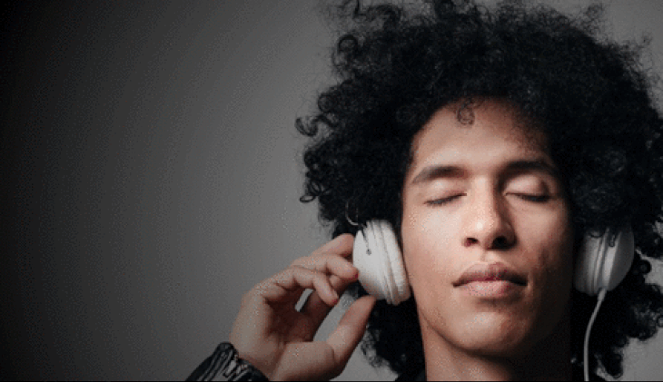 Man with afro, eyes closed, listening to music with animated notation overlay.