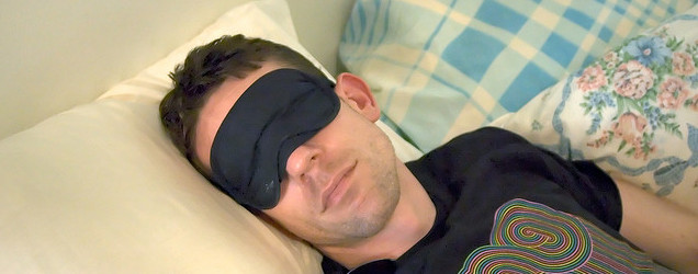 Man sleeping with blindfold on. 