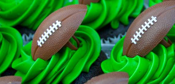 Cupcakes with green icing and football decor. 