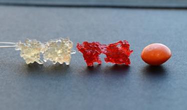 Image shows two types of model crystals, one clear and one red, with a Skittle candy nearby for scale.