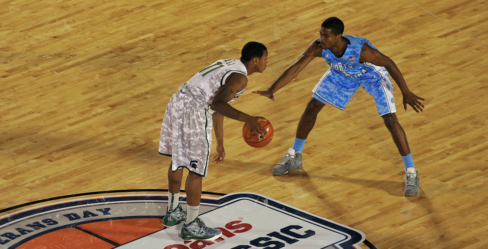 Two basketball players face off mid-court. 