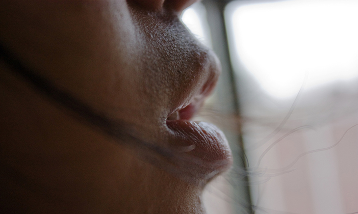 Closeup profile of a man's mouth breathing out. 