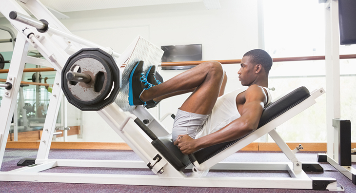 Man on leg press machine in gym. 