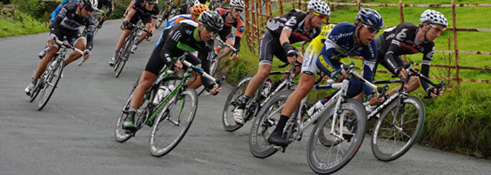 Racing bicyclists round a tight corner in a park. 