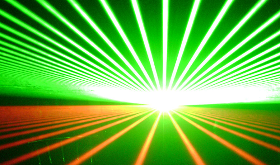 Green and red laser light spreads in many lines from a bright center point.