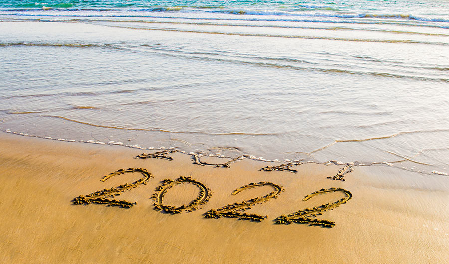 An image of the seashore, with the waves coming onshore to erase the digits 2021, with 2022 still completely legibile.