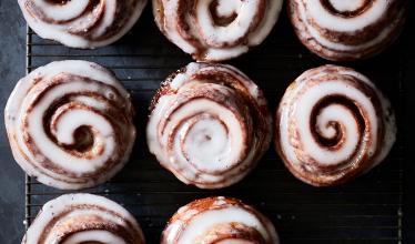 A picture of freshly baked cinnamon rolls taken from above, with white icing atop browned, coiled rolls. 