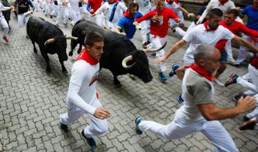 People run alongside bulls during the running of the bulls in Pamplona, Spain. 